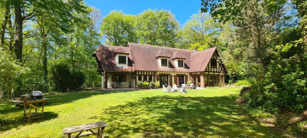 une grande maison avec deux chiens assis dans le jardin dans l'établissement Le Bois Fleuri - 7500 m² de jardin, à La Couture-Boussey