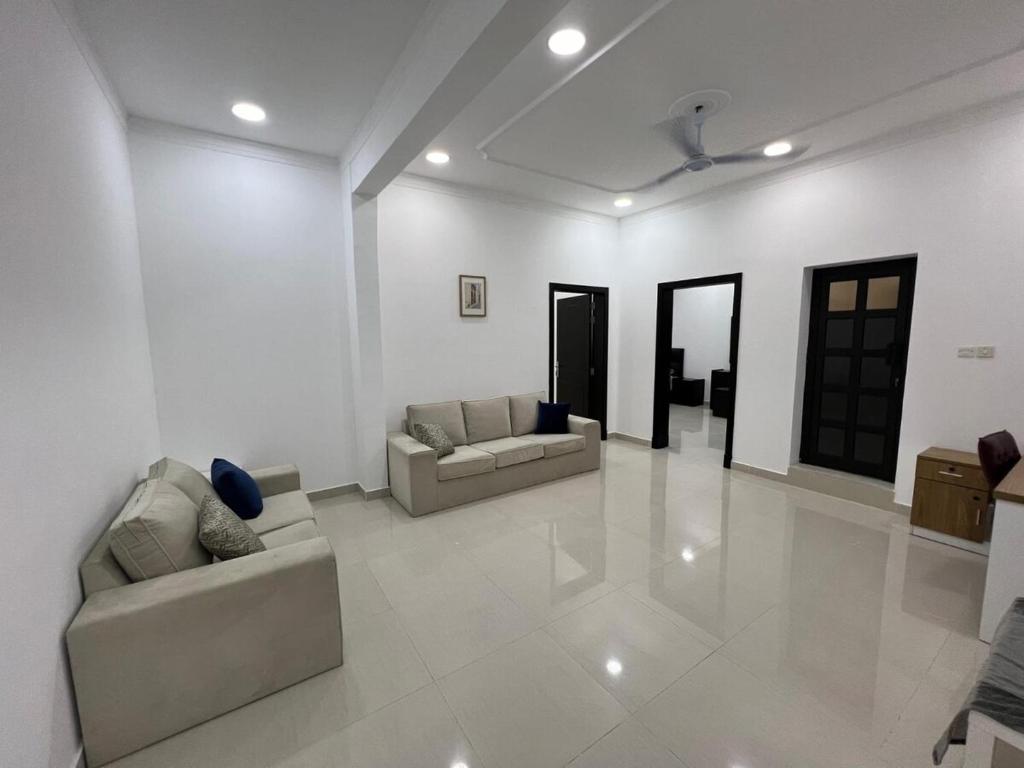 ein Wohnzimmer mit 2 Sofas und einem Deckenventilator in der Unterkunft Your Cozy Stay in Bahrain in Jurdāb
