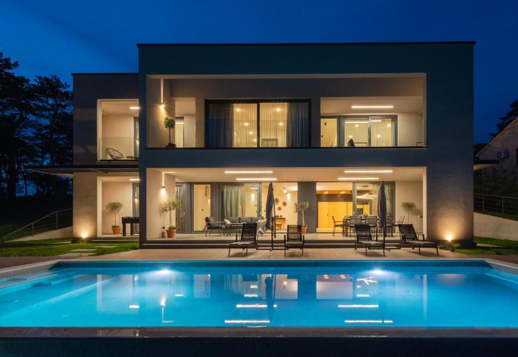 a house with a swimming pool in front of it at Villa Valpinia Luxury Villa in a Quiet Location with Pool, Sauna, Jacuzzi and Large Garden in Martinski