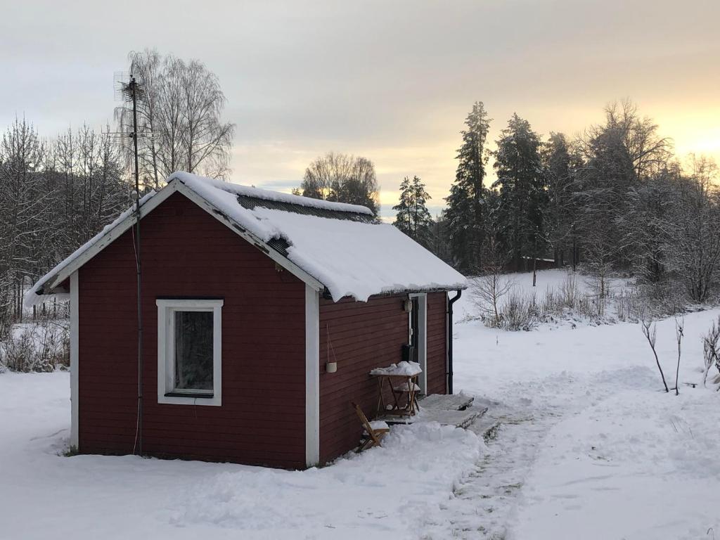 uma pequena casa vermelha com neve no telhado em Ölrun Stuga em Hammarstrand