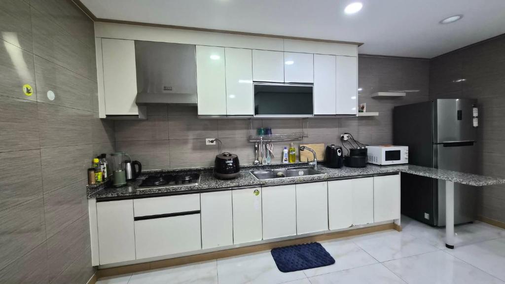 eine Küche mit weißen Schränken und einem Edelstahlkühlschrank in der Unterkunft Stay at The Villages in Sampong