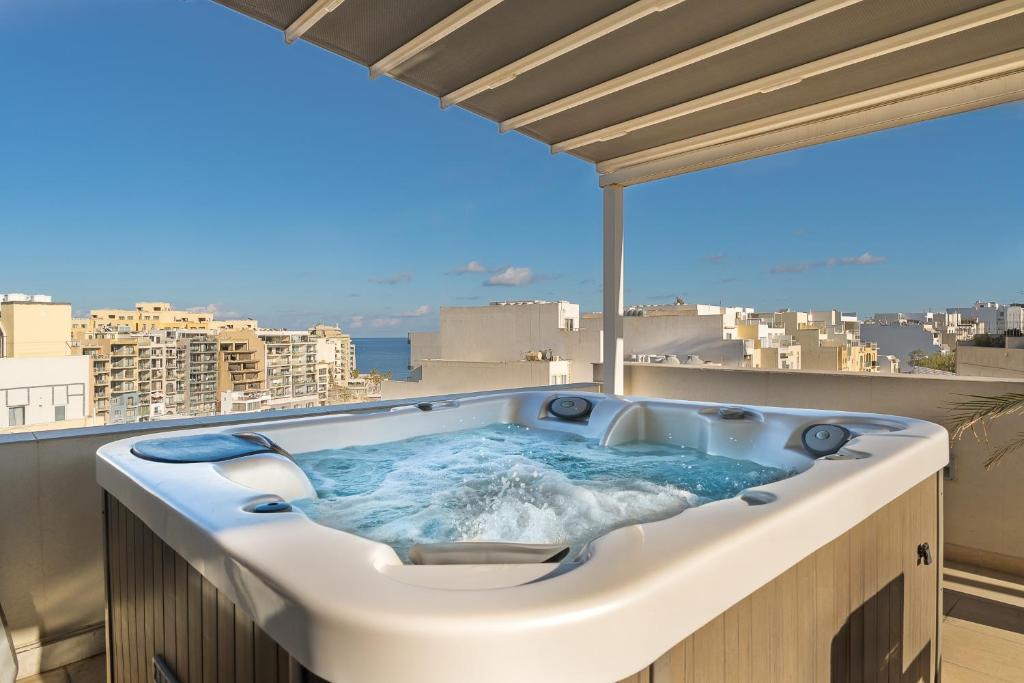 a hot tub on a balcony with a view of a city at Cherry Penthouse in Spinola Bay in St. Julianʼs