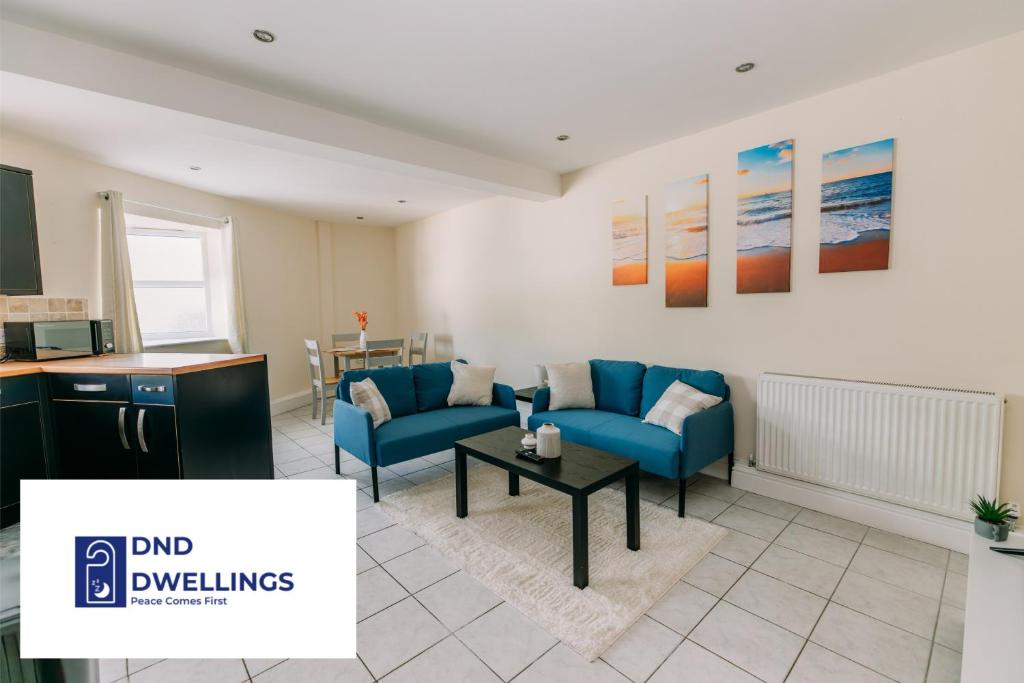 ein Wohnzimmer mit einem blauen Sofa und einem Tisch in der Unterkunft Lovely 2 Bed Flat close to Harbour with Parking in Folkestone