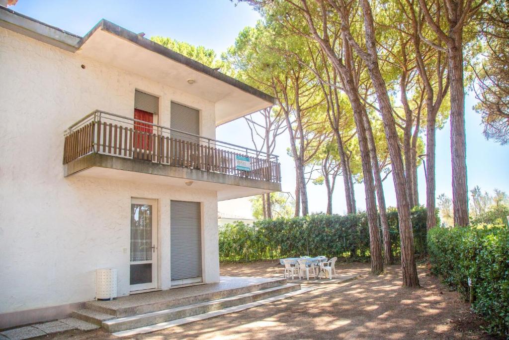 een gebouw met een balkon en tafels en bomen bij Spacious first-floor flat near the beach in Eraclea Mare