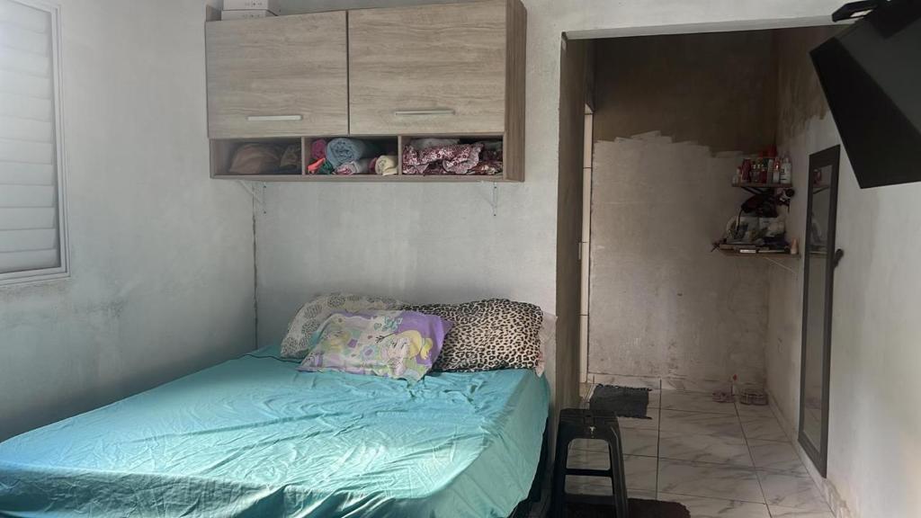 una piccola camera da letto con un letto in una stanza di casa na praia a Itanhaém