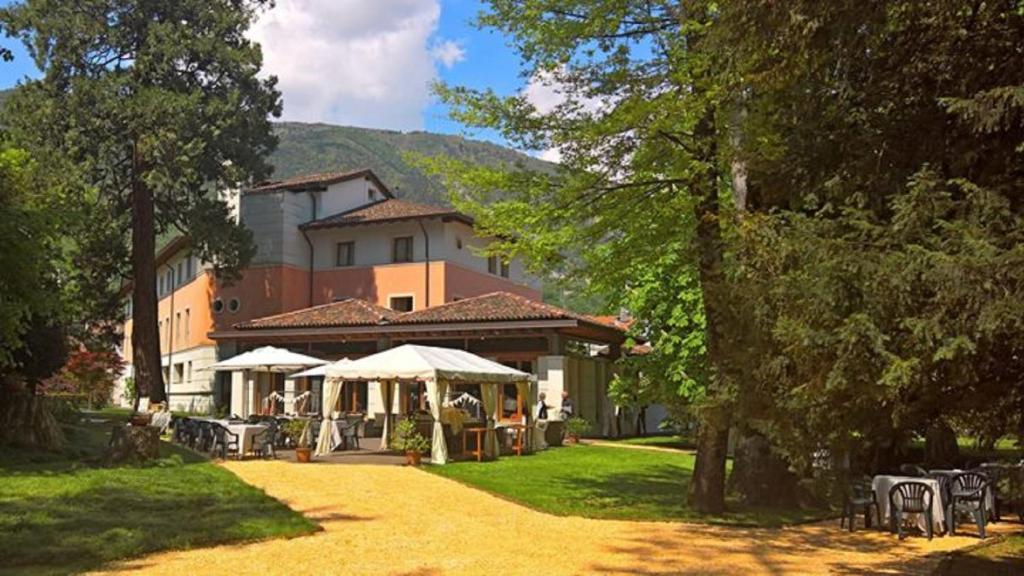 a building with tables and umbrellas in a yard at Eurohotel Palace Maniago in Maniago