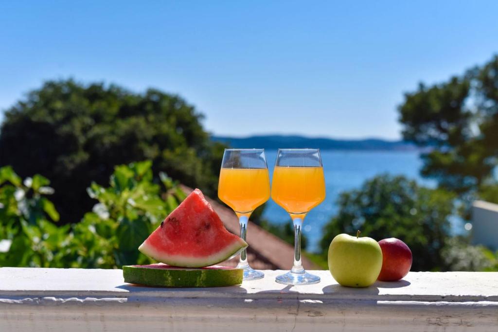 twee glazen sap en fruit op een tafel bij Beach Apartment in Bibinje