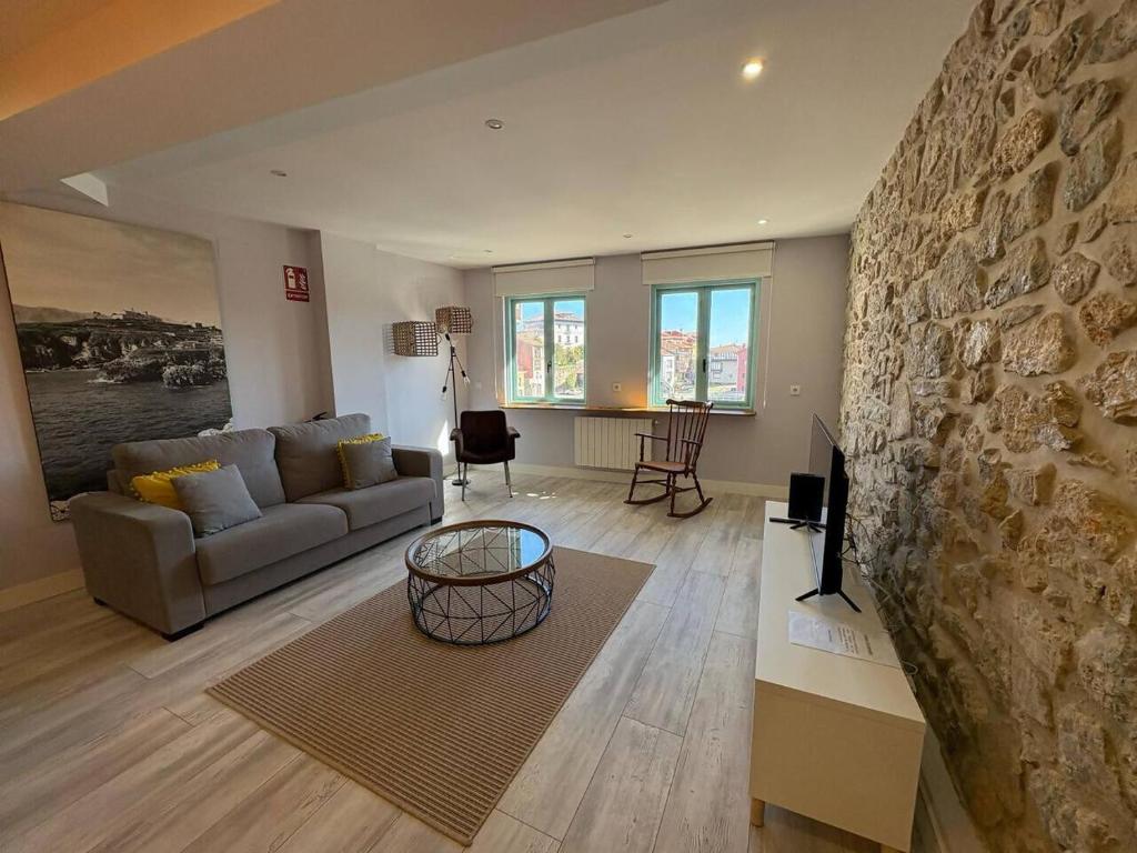 ein Wohnzimmer mit einer Couch und einer Steinwand in der Unterkunft Apartamento los Remos VUT-3207AS in Llanes