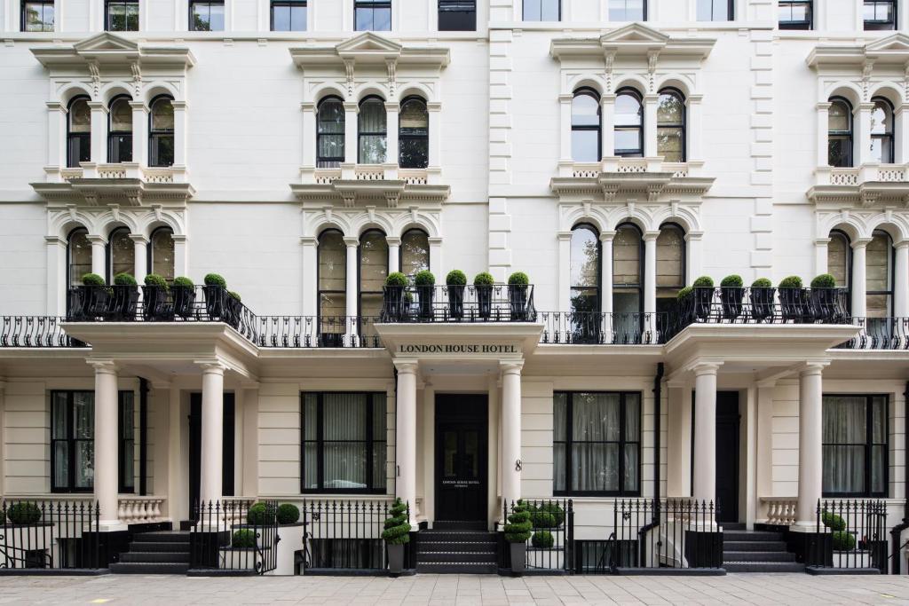 un edificio bianco con piante in vaso sul davanti di London House Hotel a Londra