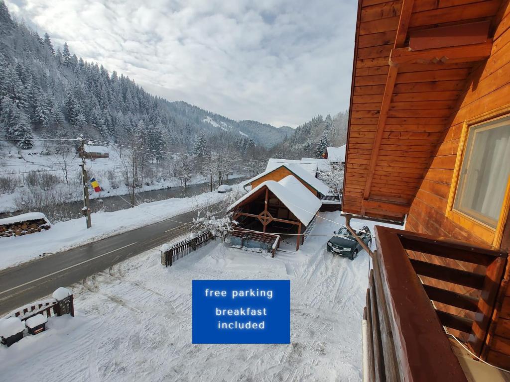 a sign on the side of a house with snow at Pensiunea Piatra Mandrutului in Scărişoara