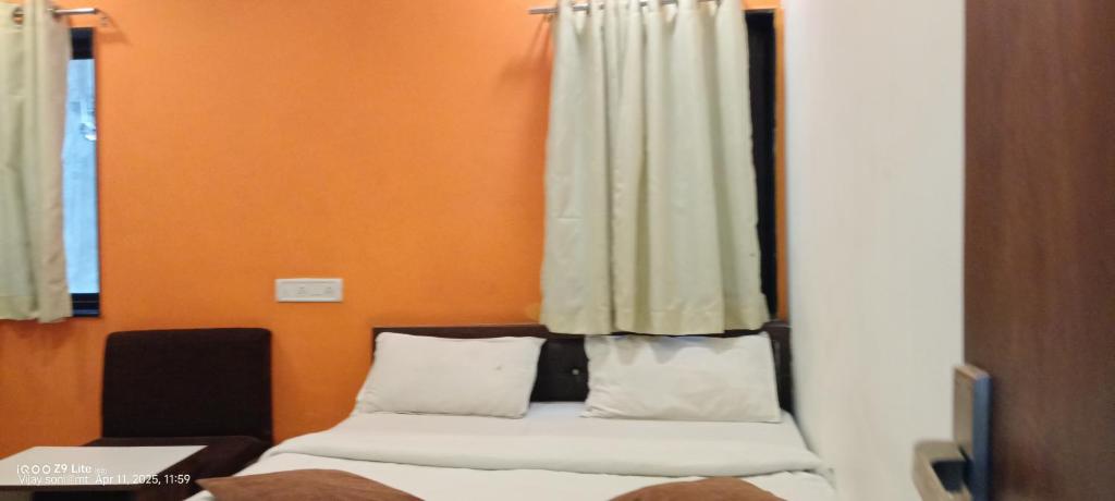 a bedroom with two beds and an orange wall at hotel VIJAY in Mount Ābu