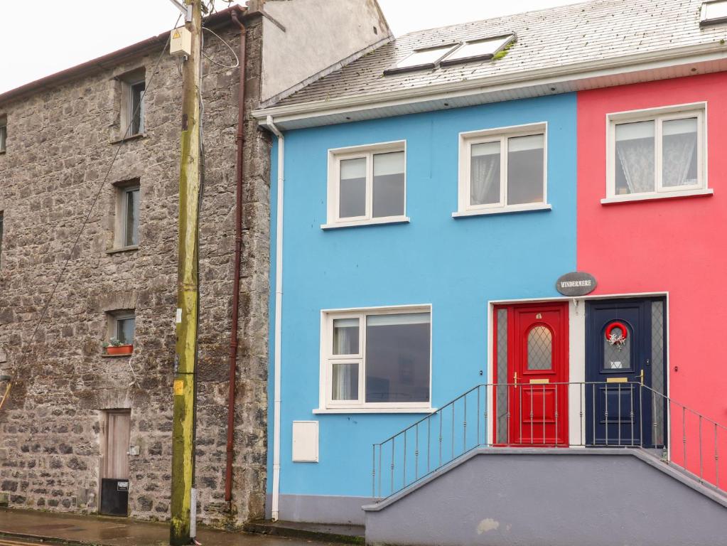 a colorful house with a red door in front at 1 Windermere in Kinvara