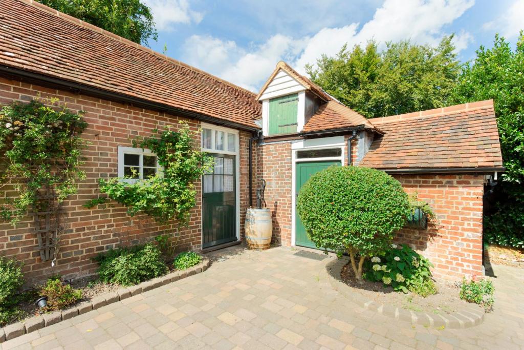 a brick house with a green window and a courtyard at The Stables at Boreham House in Herstmonceux