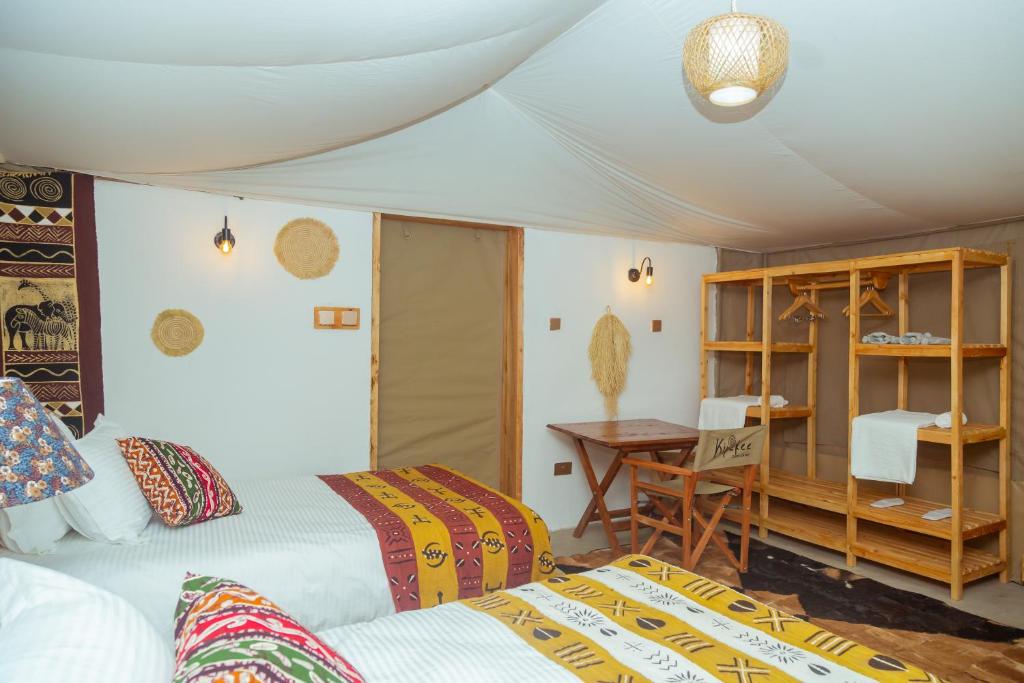 a bedroom with two beds and a table and a desk at Kipekee Zuri Camp in Ololaimutiek