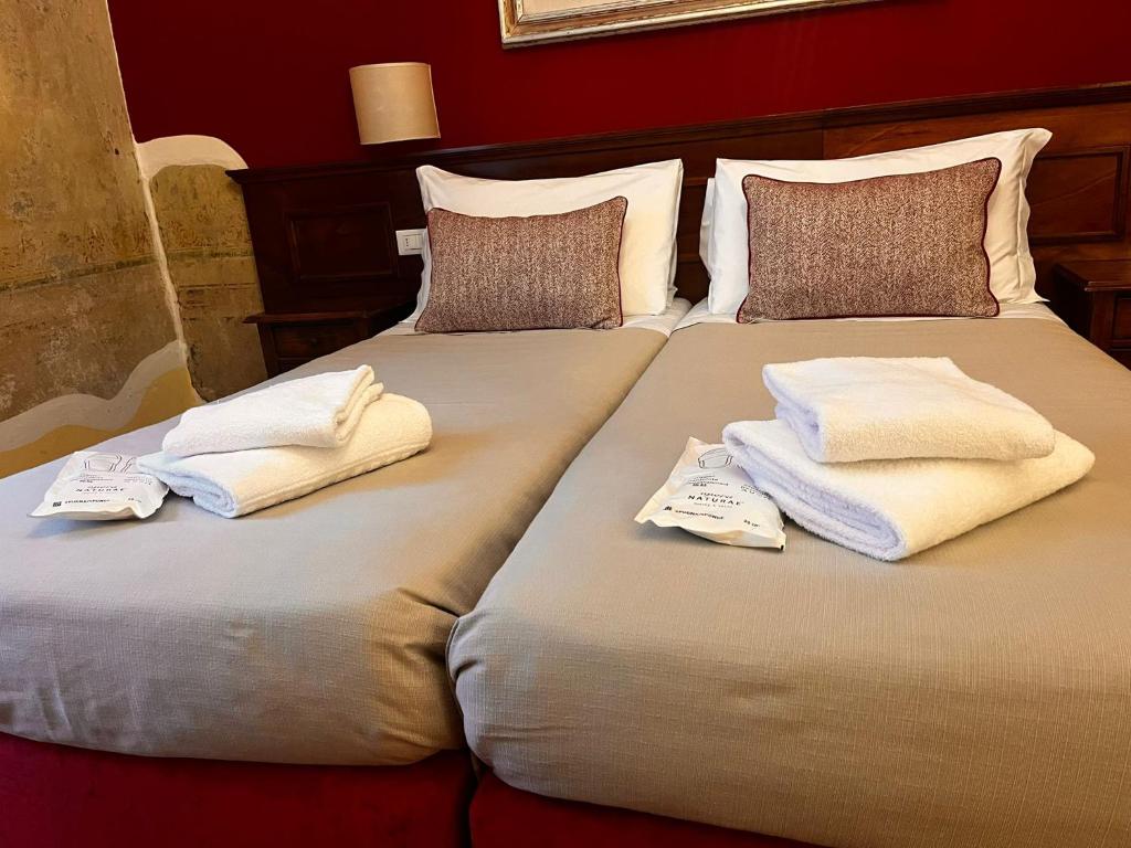 twee bedden met handdoeken en kussens erop bij Hotel Nizza in Florence