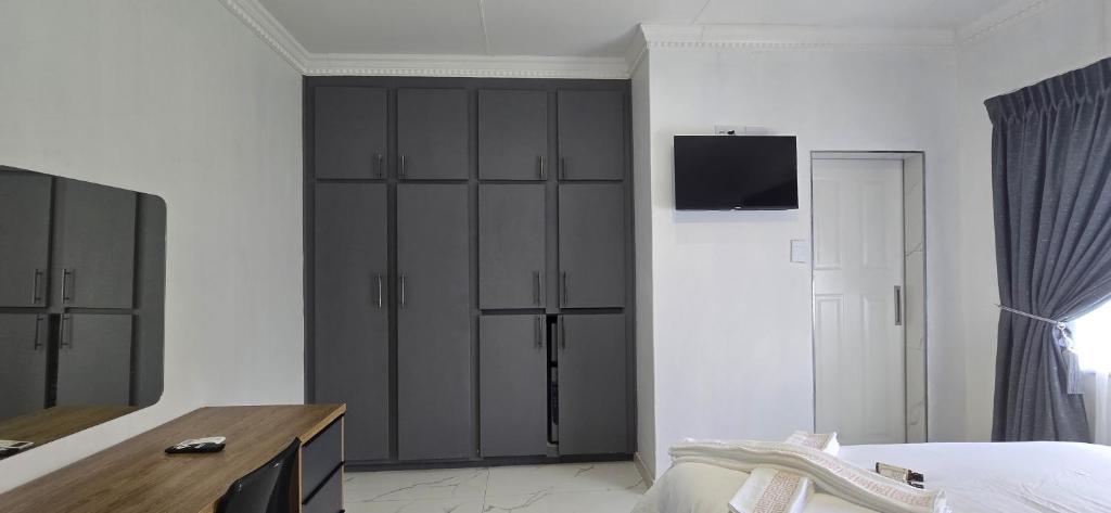 een slaapkamer met zwarte kasten en een tv aan de muur bij Good night guest house in Polokwane