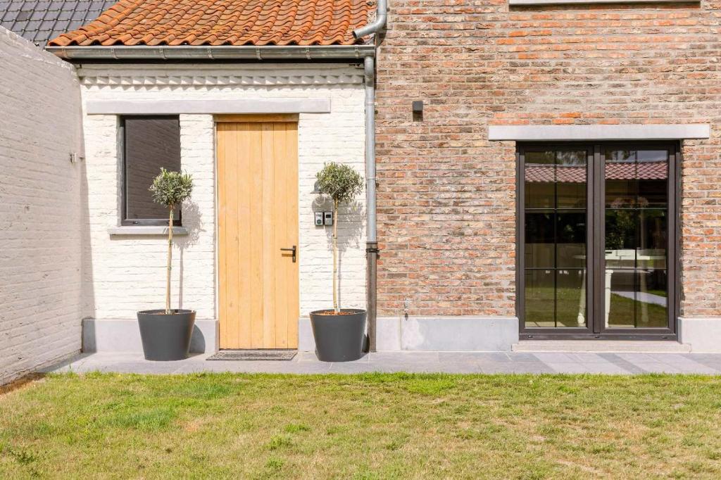 een gebouw met twee potplanten voor een deur bij Villa - The Cozy Relax Home - Comfort Nature & Style in Beernem