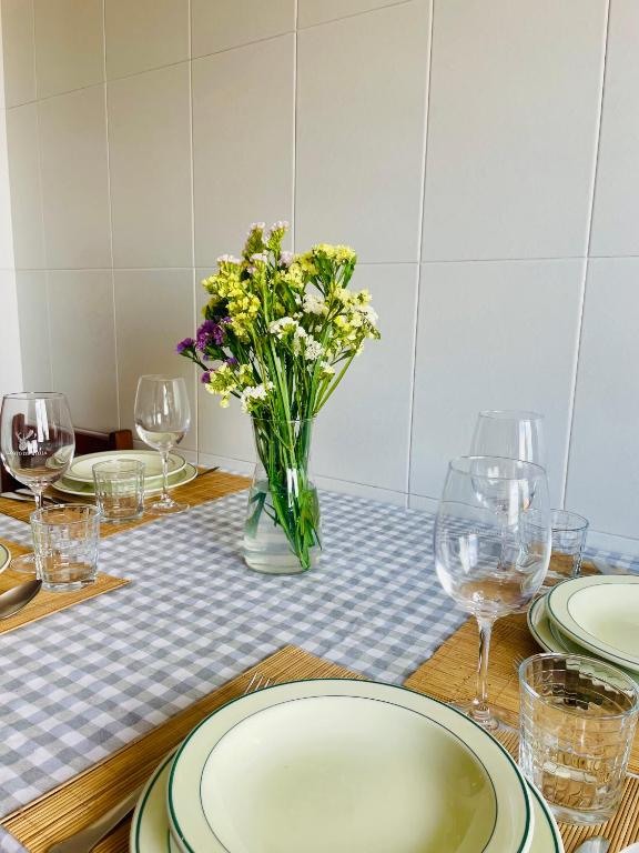 a table with plates and glasses and a vase of flowers at Lar da Amarella in Ribeira
