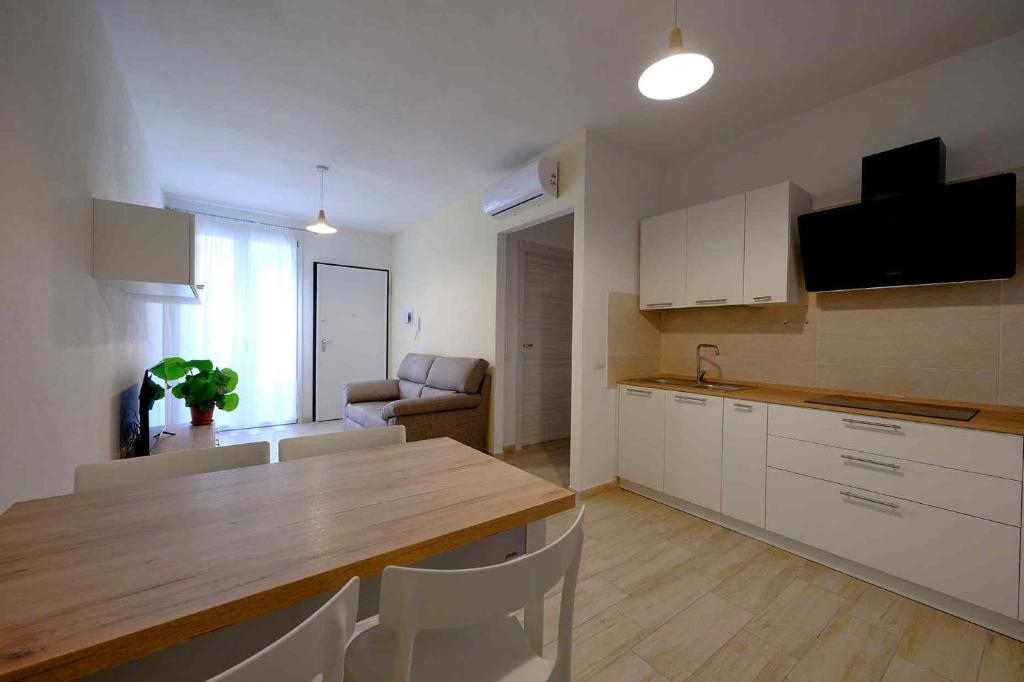 une cuisine avec une table en bois et des armoires blanches dans l'établissement Le Magie di Gioba, à Chia