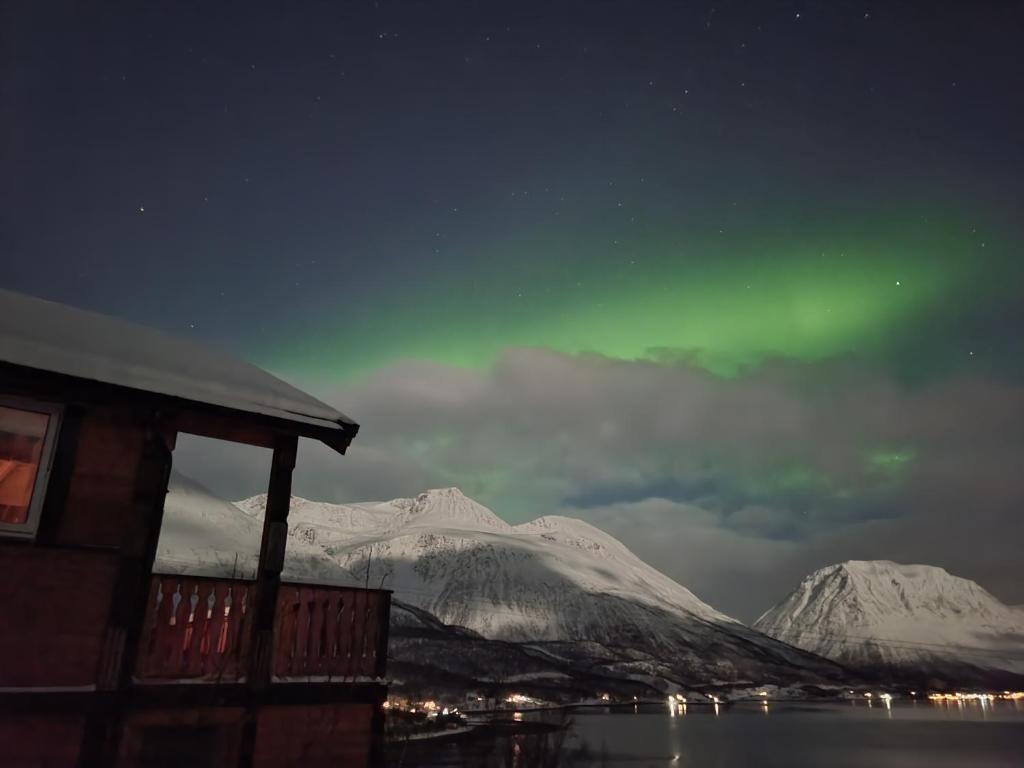 un cielo verde sopra una montagna con una casa e acqua di Sjursnes Mountain Lodge a Sjursnes
