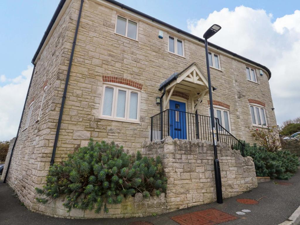 a brick house with a blue door and a street light at Ash Corner Cottage in Weymouth