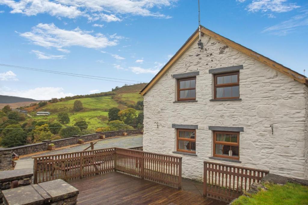 a white stone house with a wooden deck at 2 Bed in Betws-y-Coed oc-84026 in Penmachno