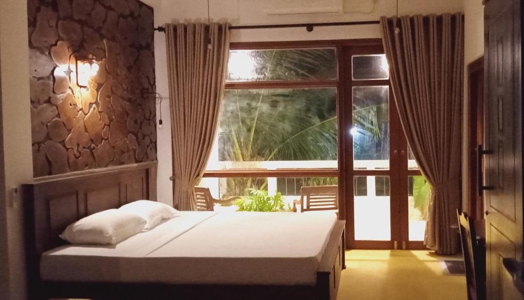 a bedroom with a bed and a large window at Guruwaththa Eco Lodge in Hikkaduwa