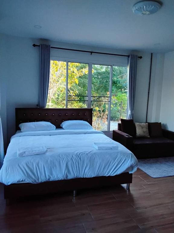 a bedroom with a bed and a large window at Huan Janto Homestay - Metta in Chiang Mai