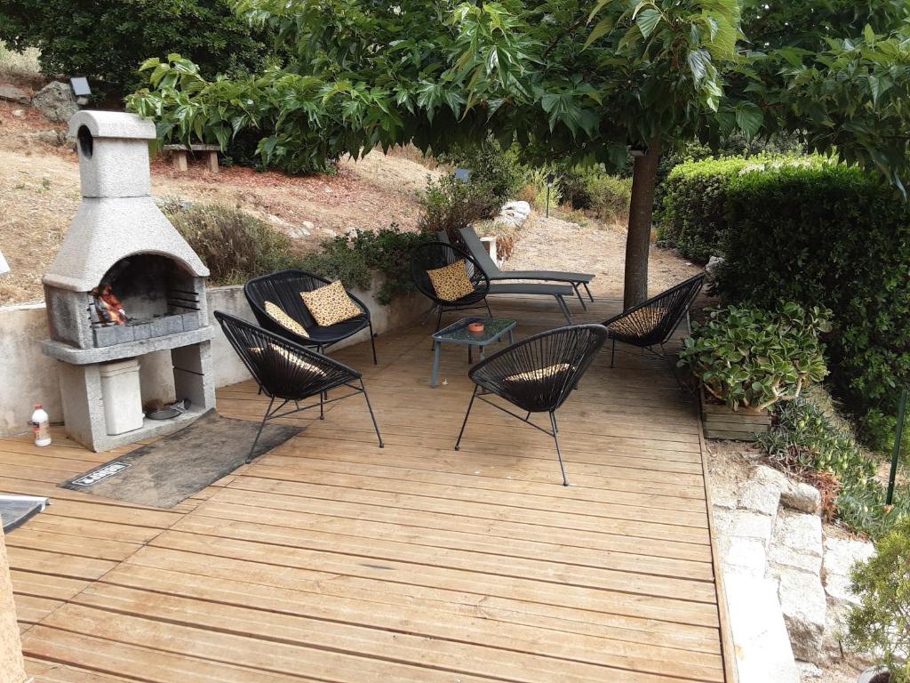 eine Holzterrasse mit Stühlen und einem Kamin in der Unterkunft La Palombière - La Bruyère in Casalabriva