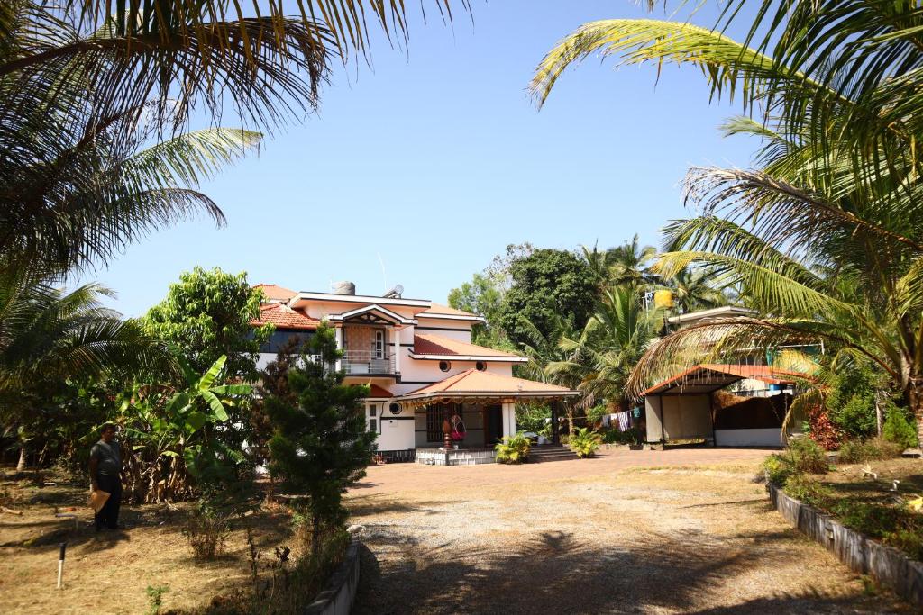 a house with palm trees in front of it at Raghavendra Homestay in Kalyānpur