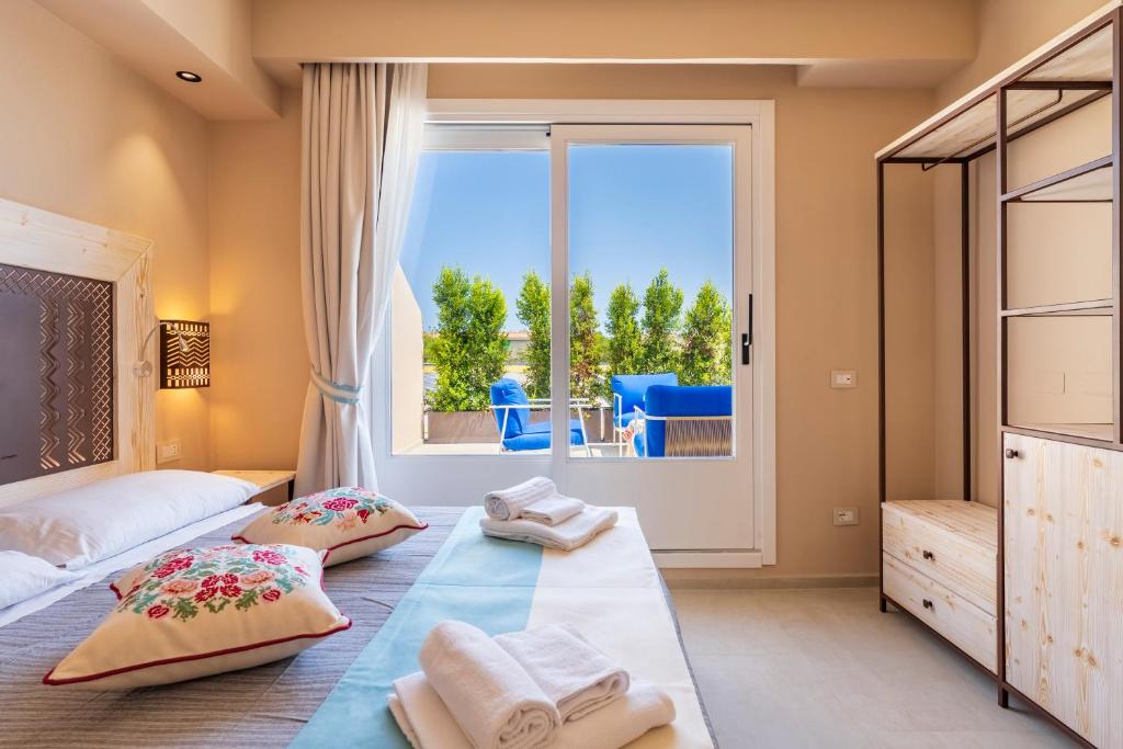 une chambre avec deux lits et une grande fenêtre dans l'établissement Nostalgia, à Tortolì