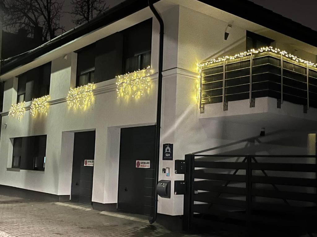 un edificio blanco con luces en el costado en S&M Apartman Nagykőrös, en Nagykőrös
