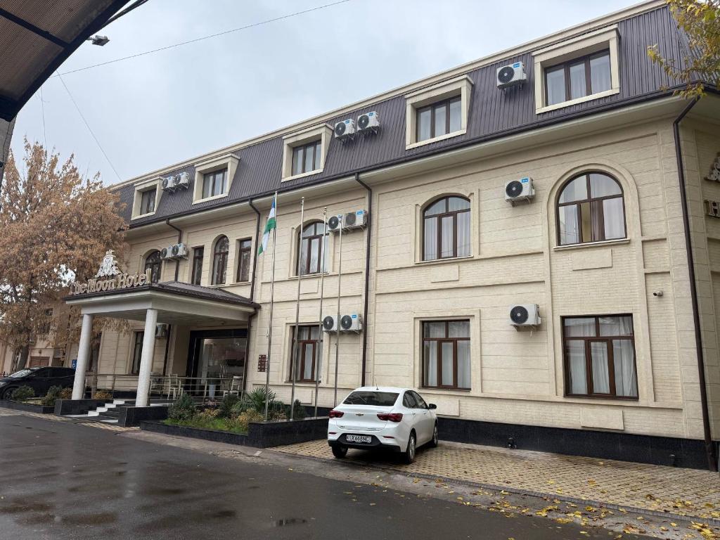 een witte auto geparkeerd voor een gebouw bij Hotel Moon in Yakkasaray