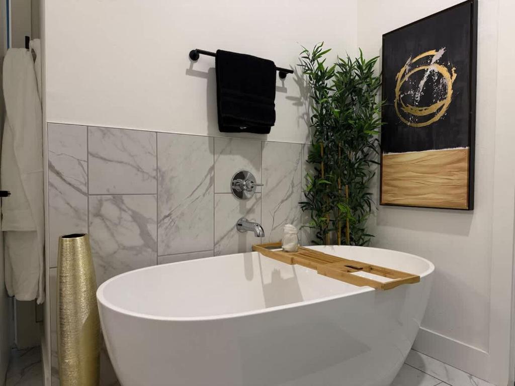 een wit bad in een badkamer met een plant bij King Beds Grill Big Yard Huge Kitchen in Oklahoma City