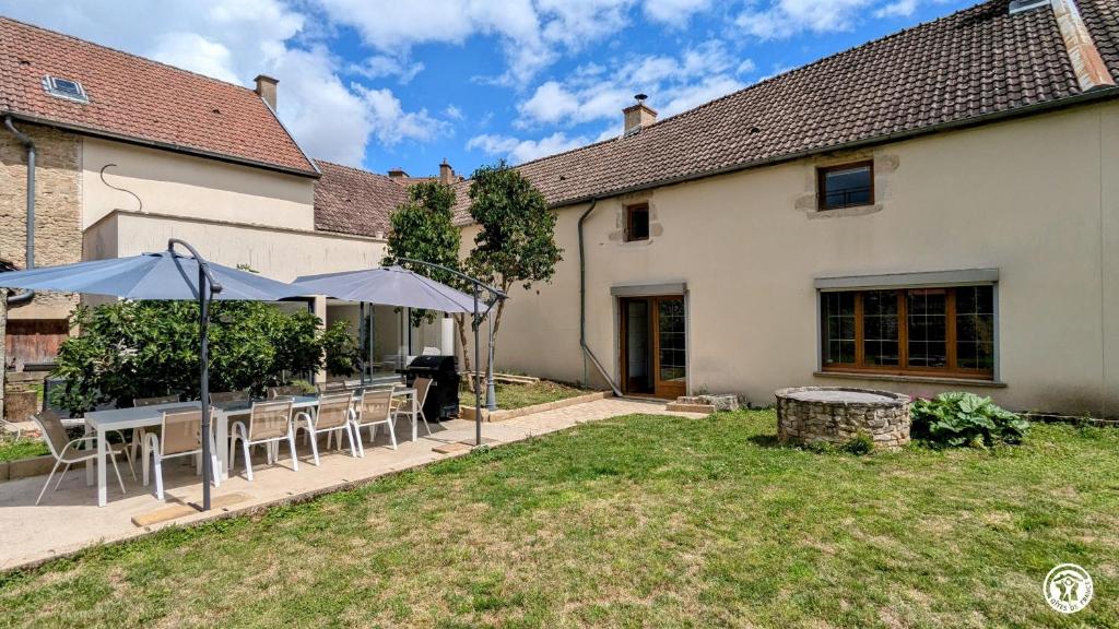 a patio with tables and umbrellas in front of a house at Ô Coeur des Liens in Saint-Seine-lʼAbbaye