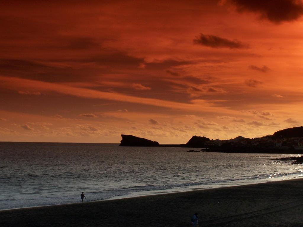 a person walking on the beach at sunset at Aparthotel Barracuda in Ponta Delgada
