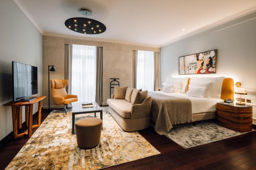 ein Schlafzimmer mit einem Bett, einer Couch und einem Fernseher in der Unterkunft MYTHIC SANA Downtown Suites in Lissabon