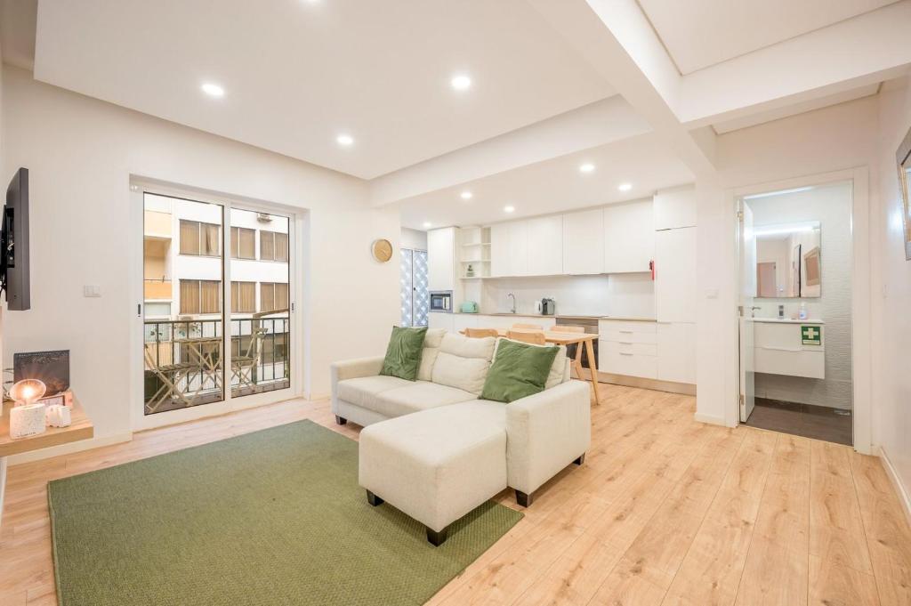 Il comprend un salon doté d'un canapé et d'une chaise ainsi qu'une cuisine. dans l'établissement GuestReady - Modern Comfort in Almada, à Almada