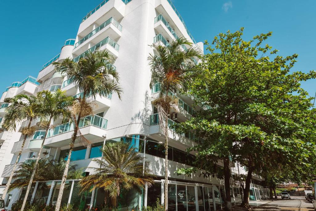 Angra Beach Hotel في انغرا دوس ريس: مبنى ابيض امامه اشجار النخيل