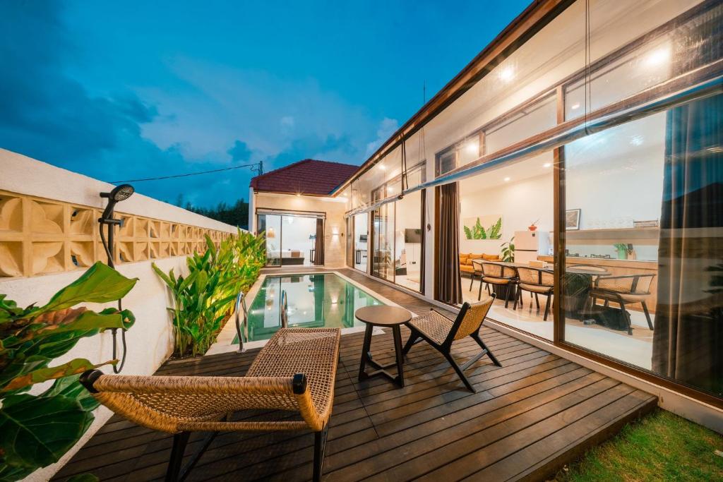 an outdoor deck with chairs and a swimming pool at Villa Gadang in Kerobokan