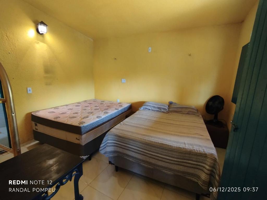 twee bedden in een kamer met gele muren bij Chalé nas Nuvens in Sobral