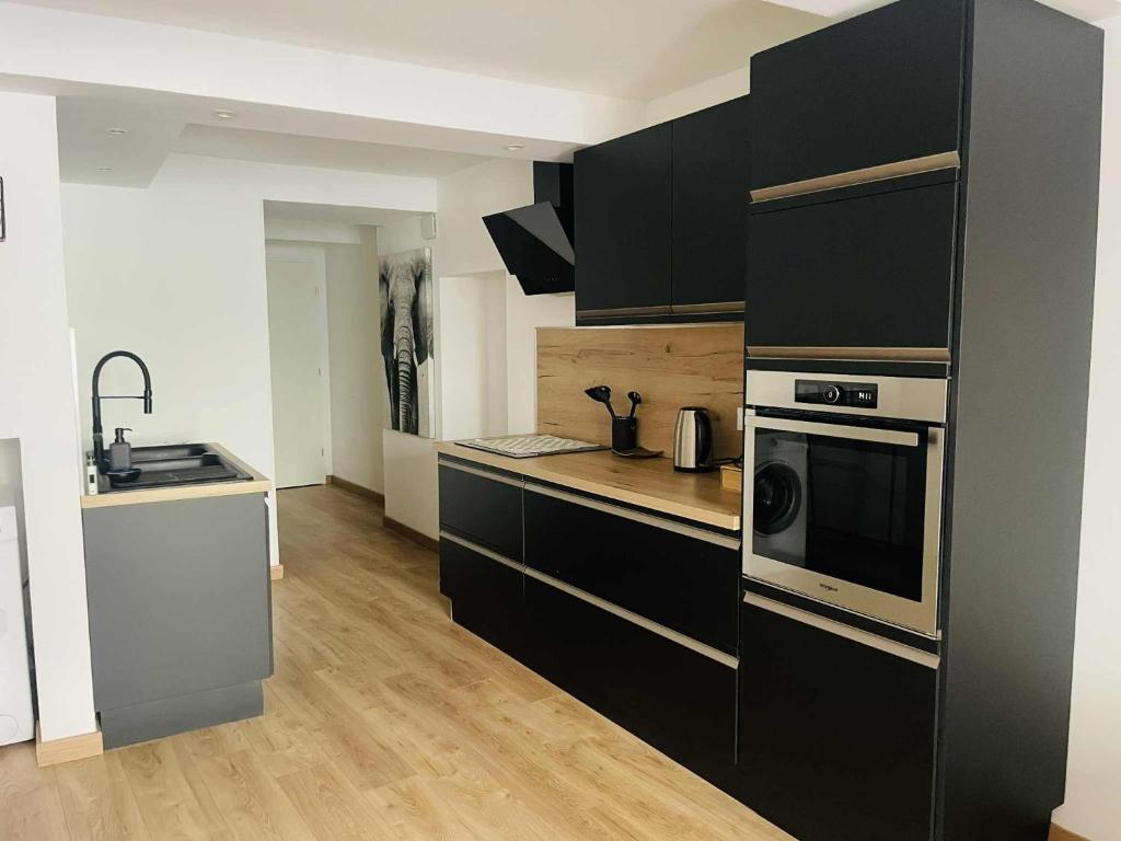 una cucina con armadi neri, lavandino e forno a microonde di Studio Bohème a La Côte-Saint-André