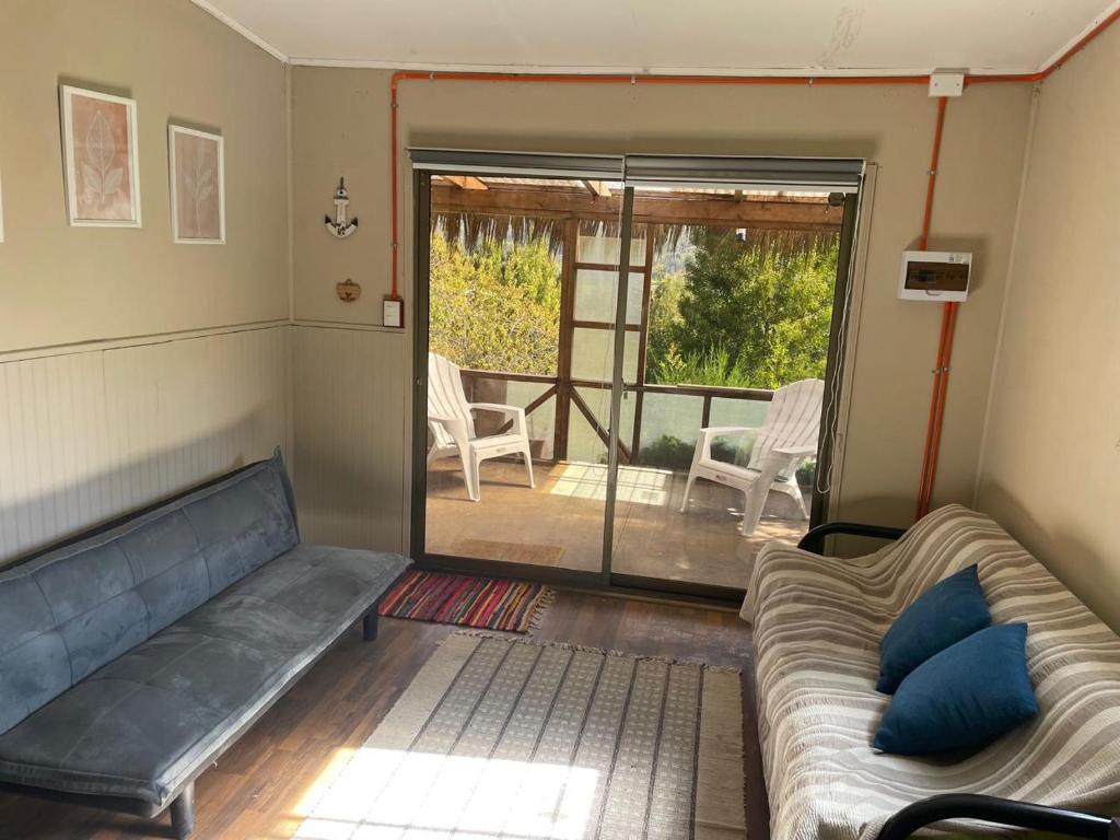 een woonkamer met een bank en een glazen schuifdeur bij casa en el lago in Contulmo