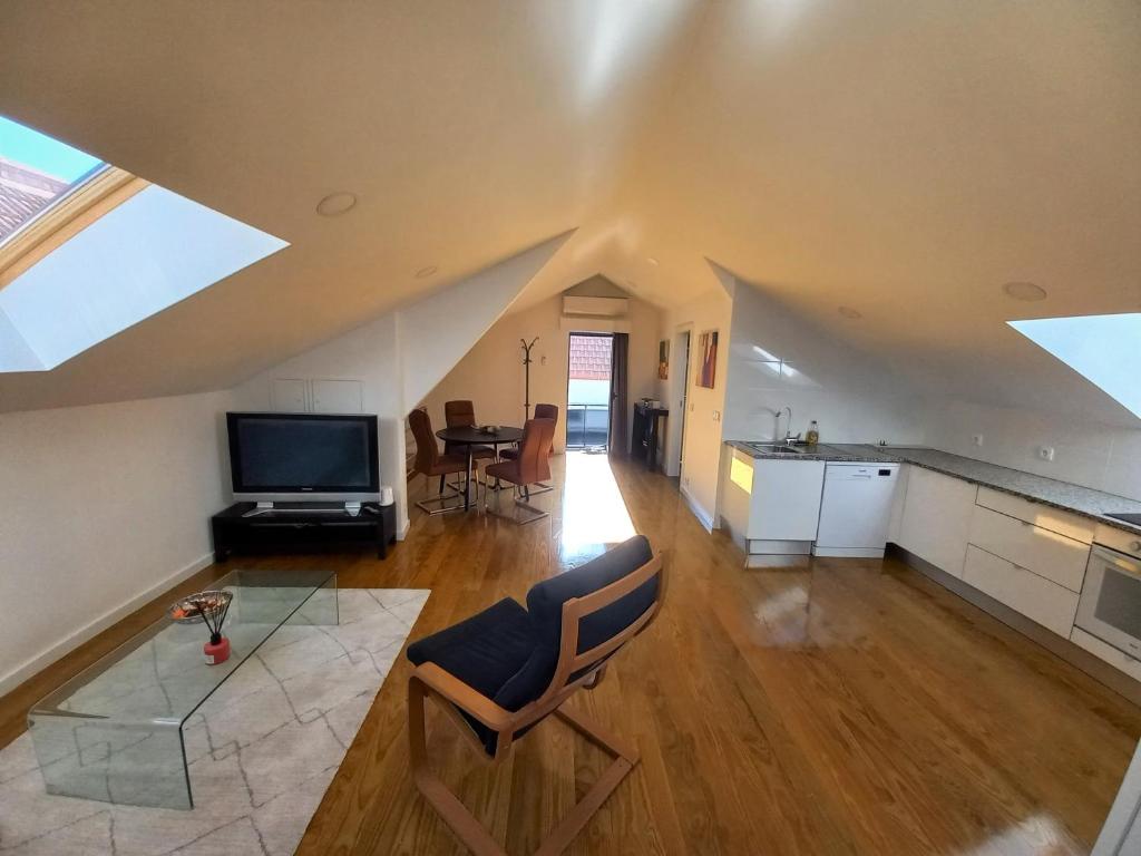 an attic living room with a kitchen and a tv at Ares do mar - Loft and terrace in Matosinhos