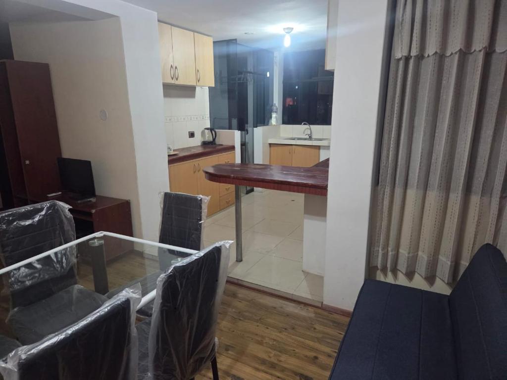 ein Zimmer mit Tisch und Stühlen und eine Küche in der Unterkunft Apartamento centrico en Puno in Puno