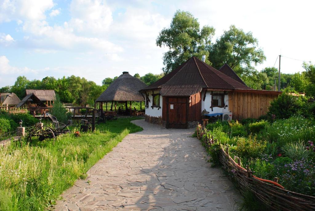 a walkway leading to two small buildings with grass roofs at Dykyi Khutir in Melʼniki