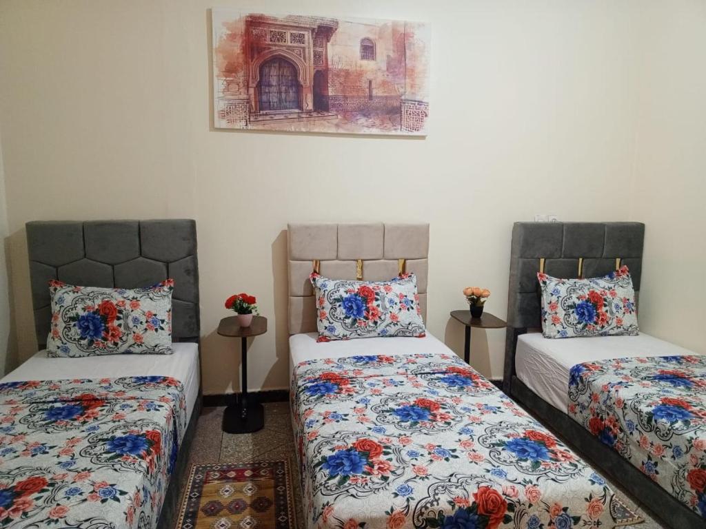 a bedroom with two beds and a painting on the wall at Royal Stay Apartment in Benguerir