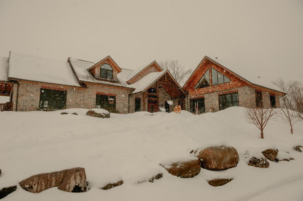 a house covered in snow with rocks in front of it at Luxury farm Stay, Alexandria in Glen Robertson