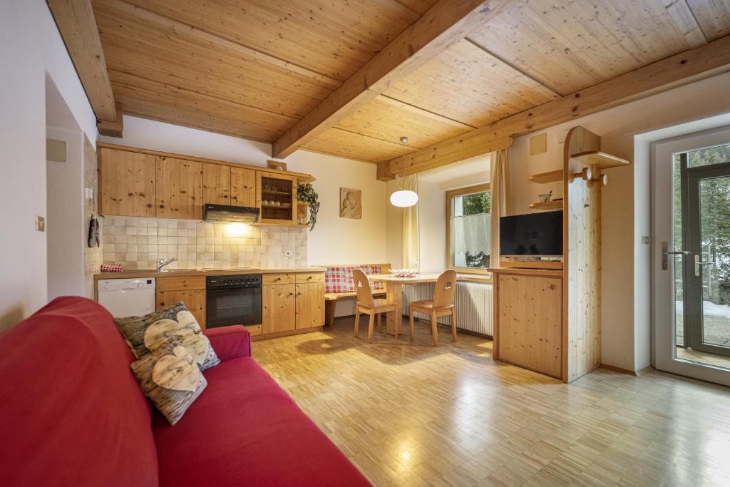 een woonkamer met een rode bank en een keuken bij Apartments Romy in Ortisei