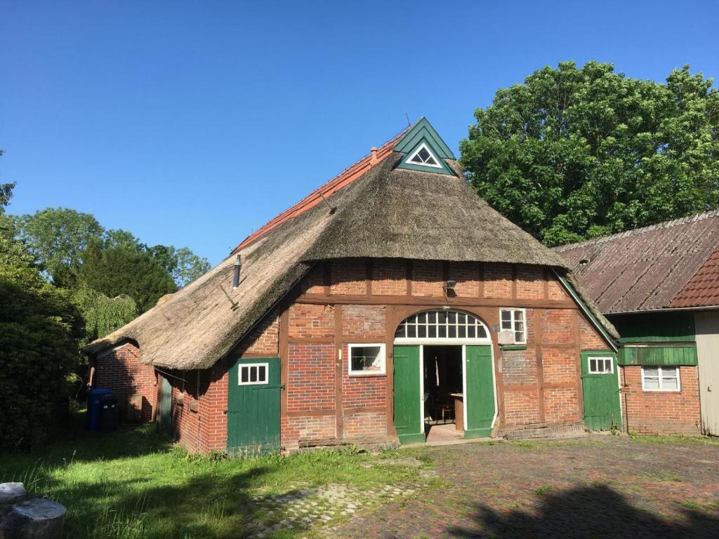 an old red brick barn with a thatched roof at Schöner alter Resthof am Jadebusen in Reitland